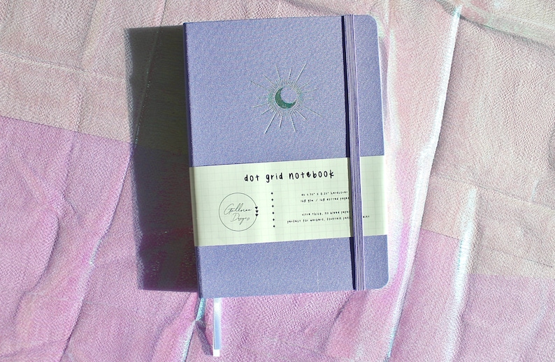 A purple dot grid notebook with a silver moon and sun design. The notebook has a white label that reads 'dot grid notebook'. Dot Grid Journal, Dot Grid Journal, Travel Journal, Reading Journal, Journals and Notebooks, Junk Journal, Dot Grid Notebook, Halloween Gift