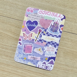 May include: A rectangular sticker with a collage design. The sticker features a purple heart with the word "Books", a butterfly, a castle, and the words "adventure" and "dream". Other elements include a magic wand and a jar labeled "Spells".