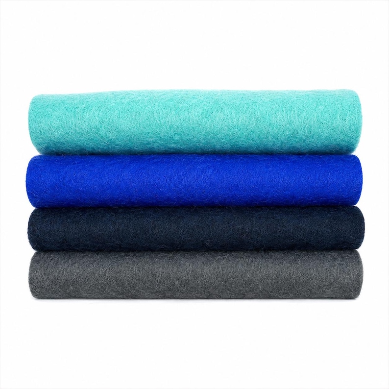 May include: A stack of four rectangular sheets of felt fabric arranged horizontally. The top sheet is turquoise, followed by a vibrant royal blue sheet, a dark navy blue sheet, and a charcoal gray sheet at the bottom. Each layer has a textured surface.