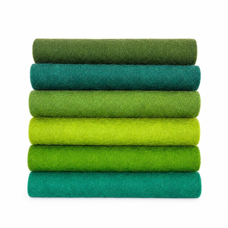 May include: A stack of six rolled sheets of felt fabric in various shades of green. The colors range from dark forest green and deep teal to vibrant lime, grass green, and emerald, all featuring a consistent, soft, and fibrous texture.