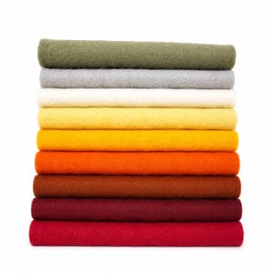 May include: A vertical stack of ten rectangular felt fabric sheets in a gradient of colors, starting from olive green at the top, followed by gray, white, light yellow, golden yellow, orange, brown, dark red, and bright red at the base.