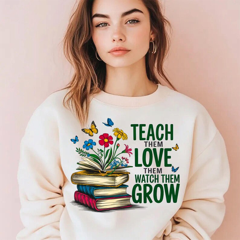 K&ouml;nnte beinhalten: Ein wei&szlig;er Pullover mit einem gr&uuml;nen, floralen Design und dem Text "Teach them love, watch them grow".