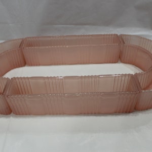 May include: A set of six pink glass dishes with a ribbed design. The dishes are arranged in a circle, with the largest dish in the center.