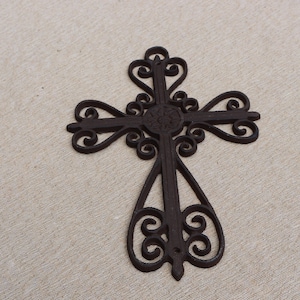 May include: A dark brown, ornate metal cross with intricate scrollwork and a circular emblem at the center. The cross has a decorative design and is set against a neutral background.