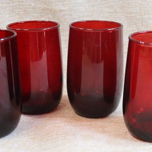 Pode incluir: Quatro copos de vinho sem haste em tom vermelho escuro. Os copos têm formato arredondado com um tom mais escuro na base, criando um efeito de gradiente. Os copos são de vidro.