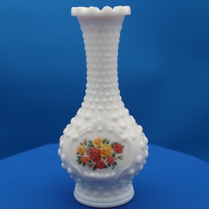 Può includere: Vaso in vetro di latte bianco con una superficie testurizzata in rilievo e un motivo floreale in tonalità di rosso, giallo e verde.