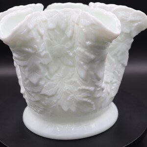 May include: White milk glass vase with a leaf design. The vase has five openings for flowers.