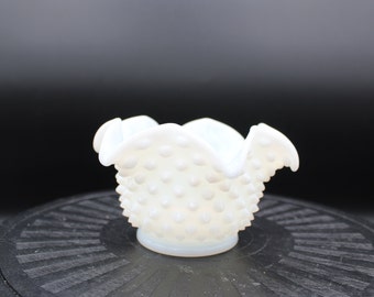 May include: A white milk glass bowl with a scalloped rim and a textured, dotted surface. The bowl is small and would be ideal for holding trinkets or small items.