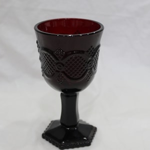 Op de afbeelding: Een donkerrode glazen kelk met een getextureerd ontwerp en een zeshoekige voet.