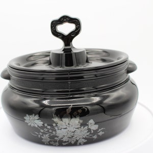 Peut inclure: Pot en céramique noire avec un motif floral argenté et un couvercle avec une poignée décorative.