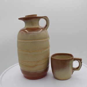 May include: A brown and beige ceramic jug with a cork stopper and a matching brown and beige ceramic mug.