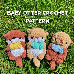 May include: Three crocheted baby otter amigurumi toys with different colored fur. The otters are holding small crocheted fish in their paws. The otters are sitting on a bed of green grass. The text "BABY OTTER CROCHET PATTERN" is at the top of the image. The text "PDF digital download only" is at the bottom of the image.