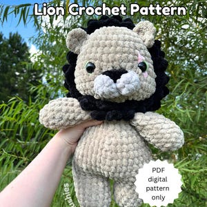 May include: A crocheted lion plush toy with black fur around its head and face. The lion has a white muzzle and pink nose. The toy is being held by a hand. The text "Lion Crochet Pattern" is at the top of the image. A white circle with the text "PDF digital pattern only" is in the lower right corner of the image.
