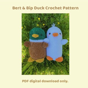 May include: Crochet pattern for two duck plushies, one green and brown and one white. The ducks are sitting on a bed of green grass with yellow flowers. The pattern is a PDF digital download only. Bert & Bip Duck Crochet Pattern.