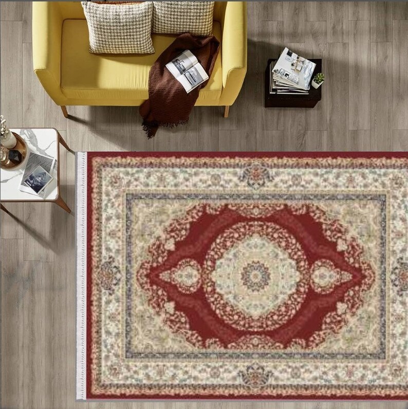 Puede incluir: Una alfombra roja con un borde crema y intrincados patrones florales. La alfombra tiene un medall&oacute;n central con un fondo crema y un borde rojo.