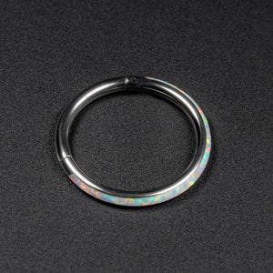 May include: A silver ring with a white opal inlay. The ring is a seamless circle with a smooth, polished finish.