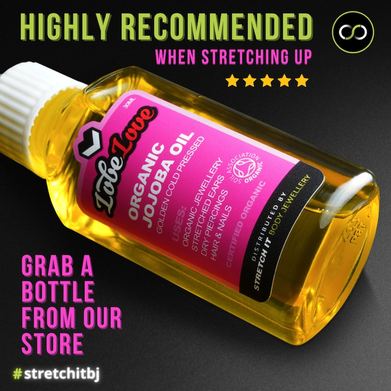 May include: A yellow bottle of organic jojoba oil labeled "Lobe Love" with a pink label that says "Organic Jojoba Oil Golden Cold Pressed" and lists uses for the oil, including organic jewelry, stretched ears, dry piercings, hair and nails. The bottle is on a black background with the text "HIGHLY RECOMMENDED WHEN STRETCHING UP" and a five-star rating.