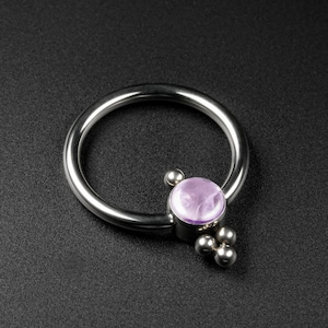 以下が含まれることがあります： 銀色のリングに紫色の宝石と、リングに付いた3つの小さな銀色のボール