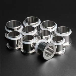 May include: A set of ten silver metal rings with a white rubber insert. The rings are stacked in a pyramid shape on a black surface.