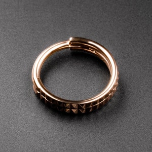 May include: A gold-toned ring with a textured, triangular pattern. The ring is made of two bands that are joined together.
