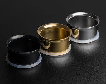 May include: Three ear gauges, one black, one gold, and one silver, with a white silicone backing. The gauges are arranged in a row from left to right.