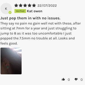 K&ouml;nnte beinhalten: Nahaufnahme eines Ohrs mit einem 7,5 mm gro&szlig;en Ohrstecker. Der Ohrstecker ist transparent mit einem gr&uuml;n-blauen Design. Die Haare der Person sind braun und der Hintergrund ist verschwommen.