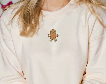 Pode incluir: Uma camisa de moletom de cor creme com um gráfico de homem de gengibre na frente. A camisa de moletom é da marca Gildan e é tamanho 1800.