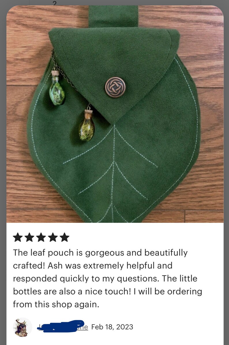 May include: A green leaf-shaped pouch with a flap closure and a decorative metal clasp. Two small glass bottles with cork stoppers and green accents hang from the pouch.