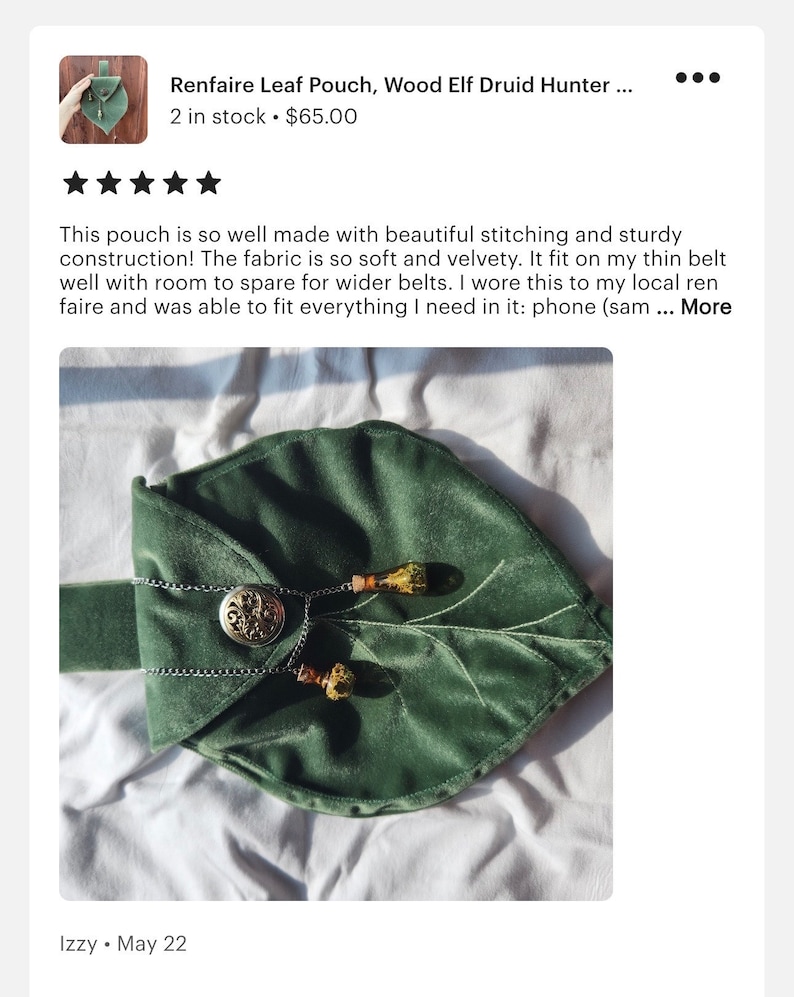 May include: A green velvet leaf-shaped pouch with a silver clasp and two decorative tassels. The pouch is lying on a white surface.