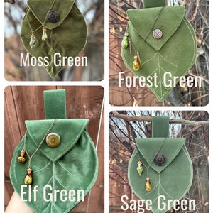May include: Four leaf-shaped pouches in different shades of green: Moss Green, Forest Green, Elf Green, and Sage Green. Each pouch has a small metal button and a chain with small glass bottles hanging from it.