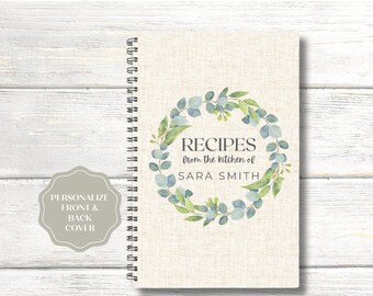 May include: A spiral bound recipe book with a beige linen cover featuring a watercolor wreath of eucalyptus leaves and the text "RECIPES from the kitchen of SARA SMITH".