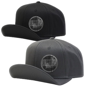 May include: Two baseball caps, one black and one dark grey, with a circular patch on the front that says "The Vintage Year".