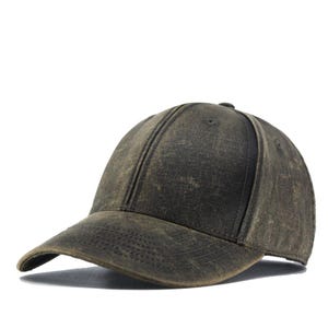 Puede incluir: Gorra de béisbol verde oliva desgastada con visera curva. La gorra tiene un aspecto vintage, con textura visible y sutiles variaciones de color. La corona presenta una costura central y un pequeño botón.