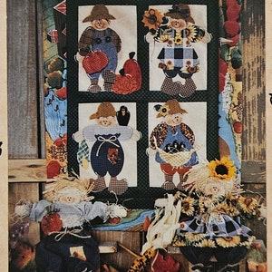 May include: A craft pattern titled KORN KEEPERS and Once upon a vine by Kim Goodrich 1994. The image features a decorative wall hanging with four scarecrow figures in a window frame, plus two fabric scarecrow dolls sitting on straw.