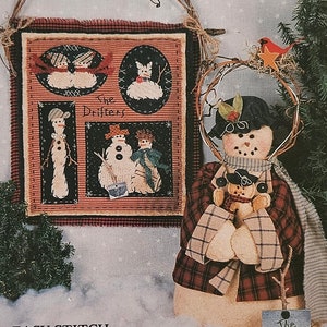 May include: A cross-stitch pattern for a snowman doorstop with a grapevine and wire carrier. The pattern is titled "The Drifters" and includes a 15-inch doorstop and a 12-inch by 14-inch embroidered snowman album quilt.
