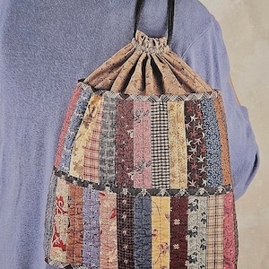 May include: A patchwork drawstring backpack pattern with the title "Kimie's Quilts" and the text "Item # LJK111 DRAWSTRING BACKPACK INDYGO JUNCTION, INC."