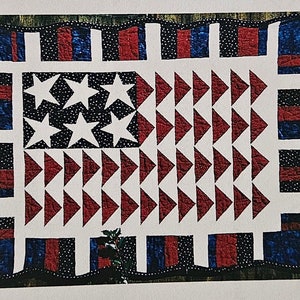 May include: A quilting pattern for a Star Salute quilt, featuring a red, white, and blue American flag design. The finished quilt size is 26 1/2 inches by 36 1/2 inches. The pattern is from The Pieceful Quilter.
