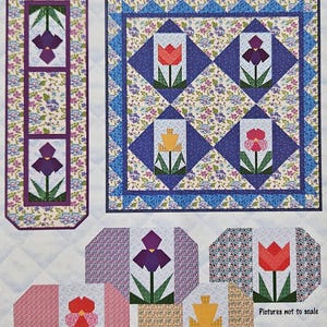 May include: A pattern for quilted placemats, wall hangings, and a tablerunner. The design features floral patterns and geometric shapes with flower motifs in red, purple, and yellow. The text "Pictures not to scale" is visible.