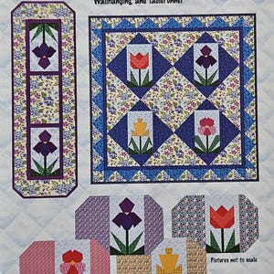 May include: A pattern for quilted placemats, wallhanging, and tablerunner. The design features floral patterns with tulips and irises in various colours, including red, purple, and yellow. The text "Get Set for Spring" is displayed at the top.