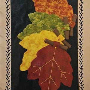 May include: A pattern for making autumn leaf placemats and napkins. The pattern features four leaves in shades of red, yellow, and green. The pattern is titled "Autumn Leaves Placemats" and includes the text "15" x 18" Placemats & Napkins" and "#180".