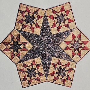 May include: A star-shaped quilt block with a central dark blue star and surrounding star patterns. The design incorporates red, tan, and dark blue colors, creating a geometric pattern. The quilt block is likely handmade.