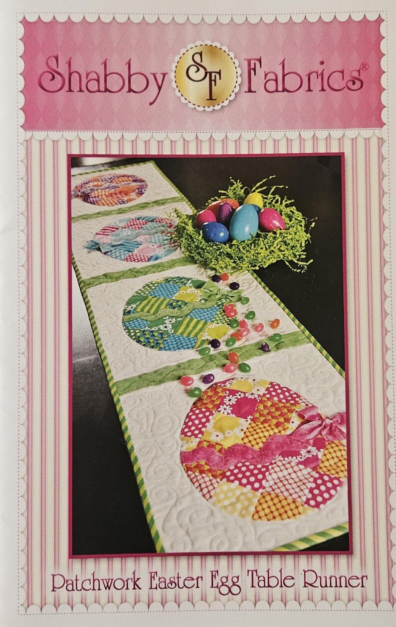 K&ouml;nnte beinhalten: Ein Patchwork-Ostereier-Tischl&auml;ufer mit wei&szlig;em Hintergrund und gr&uuml;ner Umrandung. Der L&auml;ufer zeigt bunte, gemusterte Osterei-Designs, ein Nest mit Eiern und verstreute Geleebohnen. Der Text "Shabby Fabrics" steht oben.