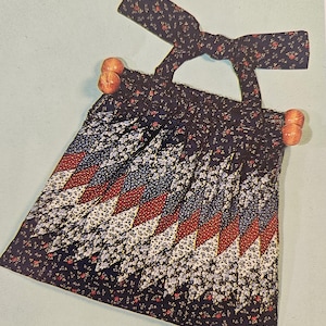 May include: A black and white floral fabric purse with a red and blue geometric pattern. The purse has a fabric handle with wooden beads on the ends. The text "NEED TO PURCHASE: FABRIC - for purse and strap" is visible at the bottom of the image.