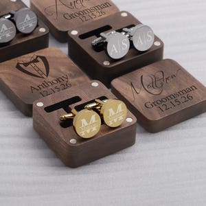 May include: Set of six wooden boxes with engraved names and dates. Each box contains a pair of cufflinks. The cufflinks are gold and silver.