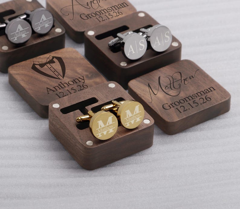 May include: Set of six wooden boxes with engraved names and dates. Each box contains a pair of cufflinks. The cufflinks are gold and silver.