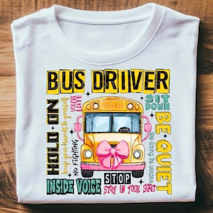 May include: A white t-shirt with a yellow school bus graphic and text that says "Bus Driver" and includes rules for riding the bus, such as "Hold On", "Keep your hands to yourself", "No Fighting", "Sit Down", "Be Quiet", "Stop", "Inside Voice", and "Stay in your seat".