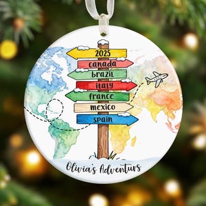 Puede incluir: Una taza de cerámica blanca con un asa negra y el texto "But First, Coffee" en negrita negra. La taza se encuentra sobre un fondo borroso, resaltando su diseño limpio.