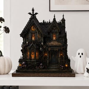May include: A dark, gothic-style miniature house model labeled The Robert Family, featuring intricate architectural details, illuminated windows with ghost figures, a bat silhouette on the roof, and decorative skulls, all set on a wooden base.