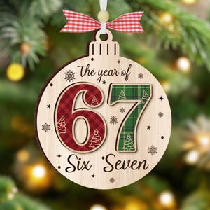 May include: Wooden Christmas ornament with the text "The year of 67 Six Seven". The number 6 is red plaid, and the number 7 is green plaid. The ornament has a white ribbon and a red and white checkered bow.