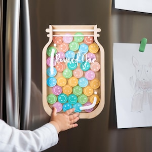May include: A wooden reward jar with a clear front and a white inscription that reads "Reward Jar". The jar is filled with colorful smiley face stickers.